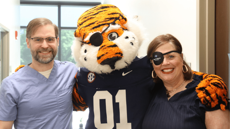 A doctor, Aubie the Tiger, and patient pose for photo at the Spencer Cancer Center